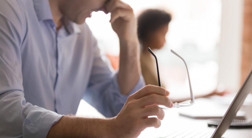 Eyestrain concept, tired businessman holding glasses rubbing dry irritable eyes